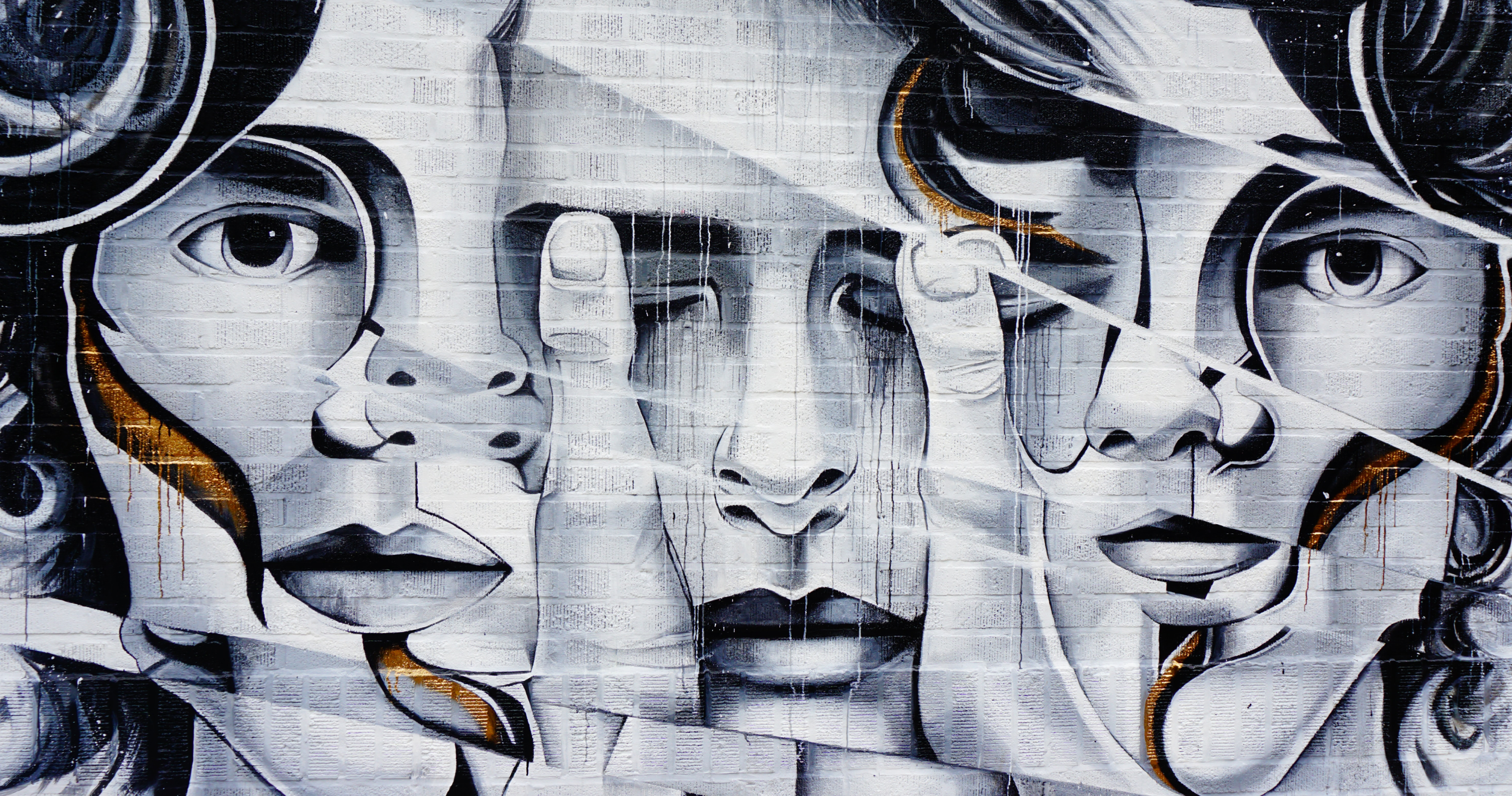 Black-and-white mural of stylized faces painted on a brick wall